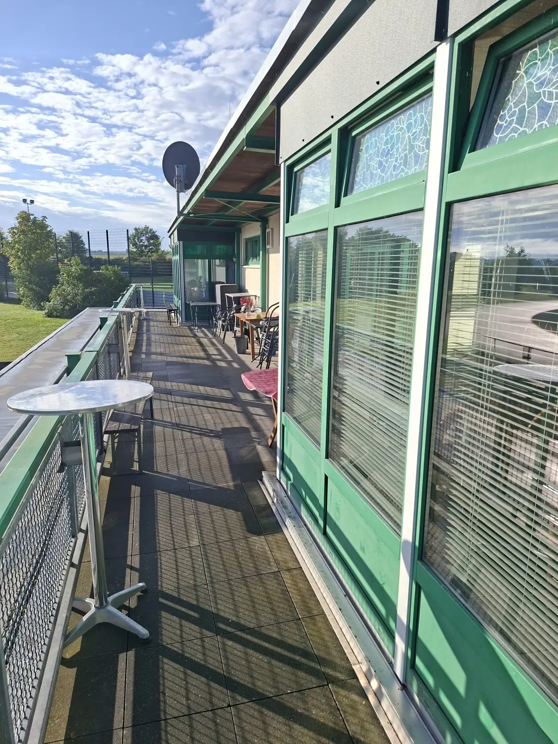 Terrassengang entlang der grün abgesetzten Hausfassade mit Sitzplätzen